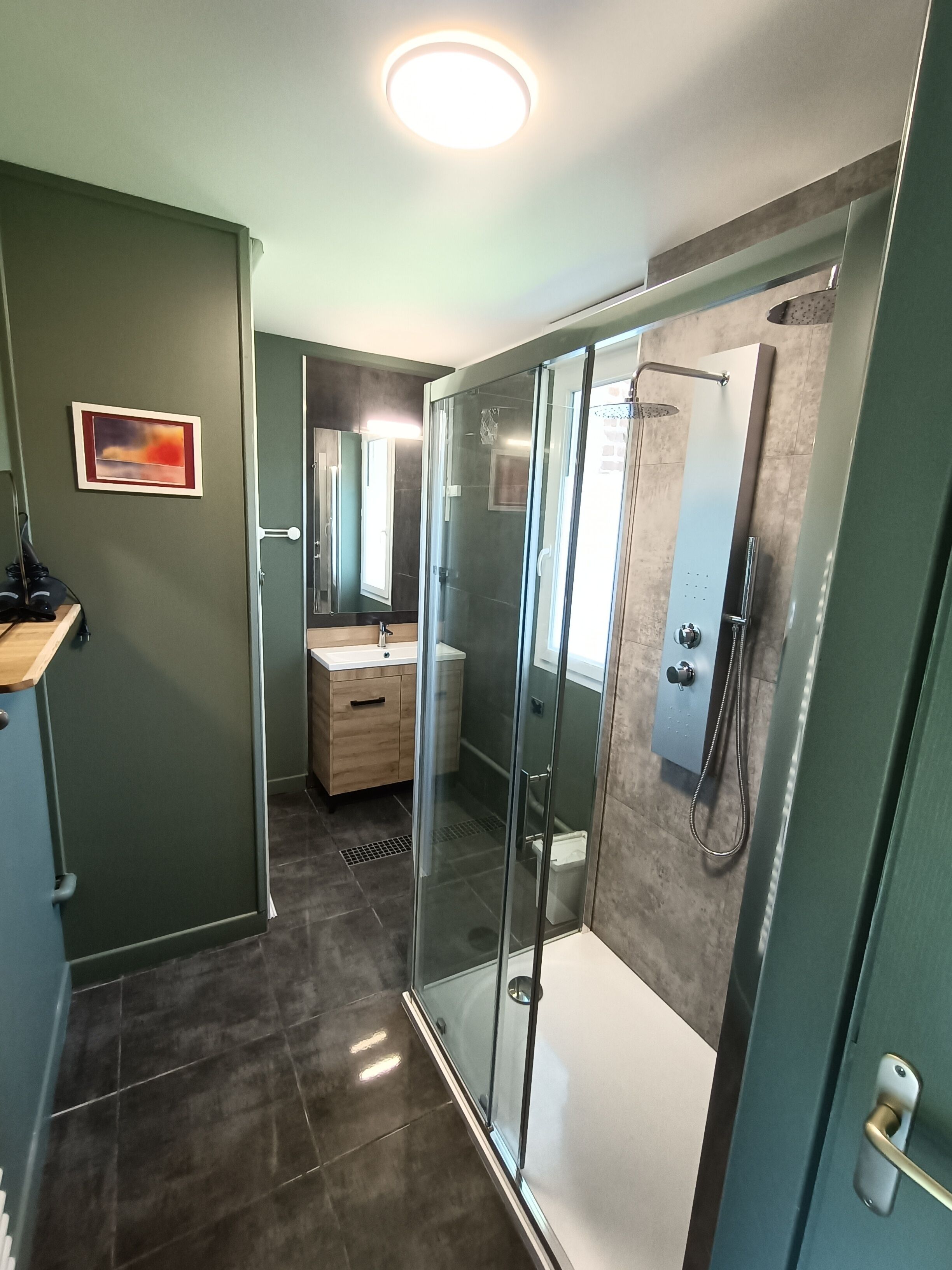 A modern bathroom with a glass shower enclosure, a vanity with a mirror, and a recessed ceiling light.