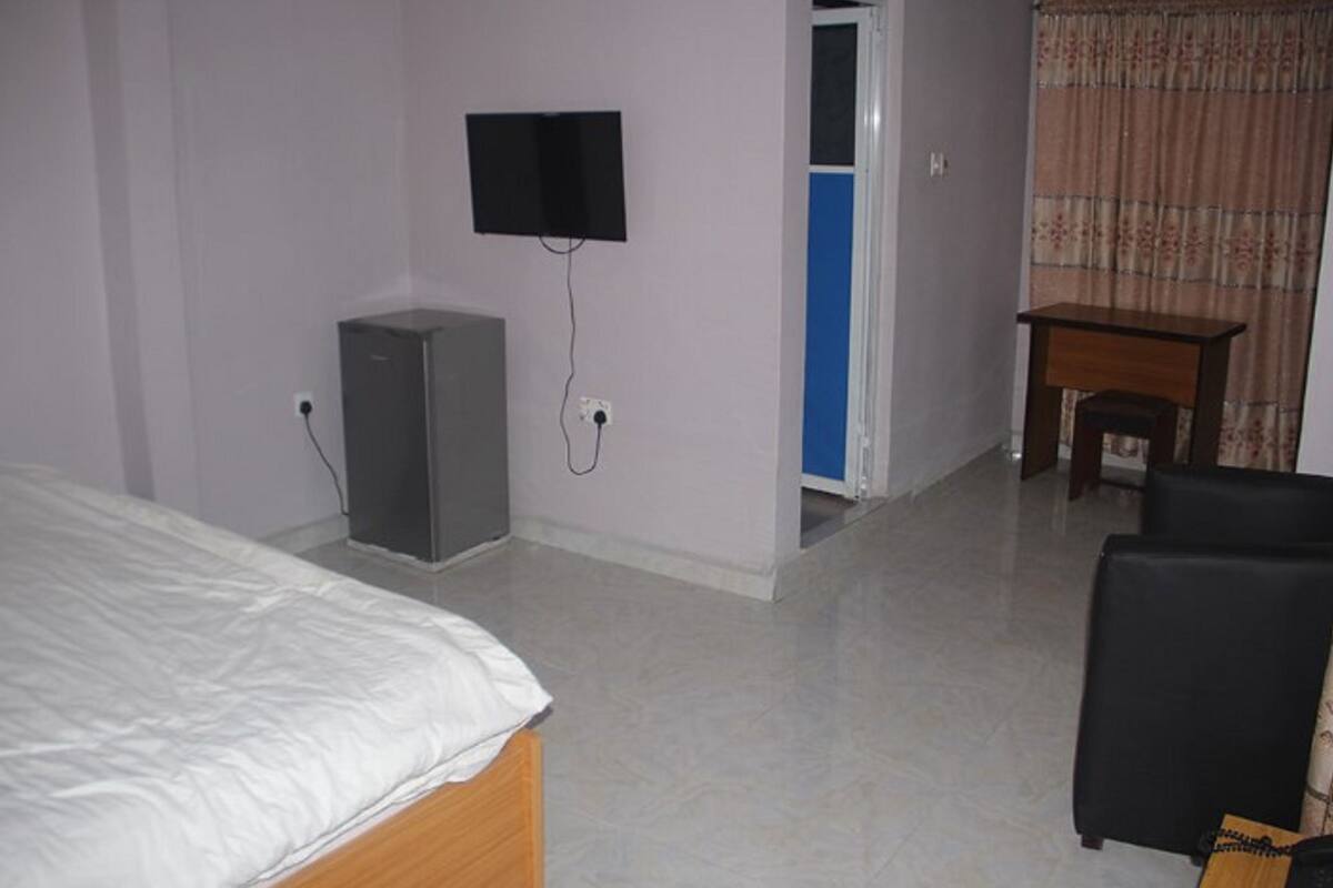 Une chambre d’hôtel équipée d’un lit, d’un bureau, d’une télévision et d’une armoire.