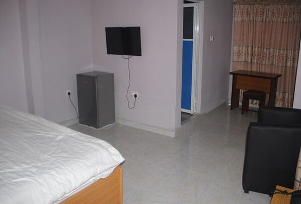 Une chambre d’hôtel équipée d’un lit, d’un bureau, d’une télévision et d’une armoire.