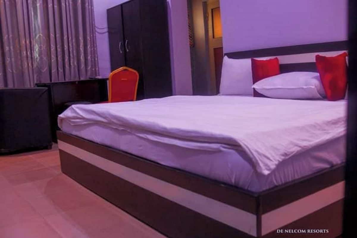 Une chambre d’hôtel avec un grand lit, une armoire, un bureau et une chaise.