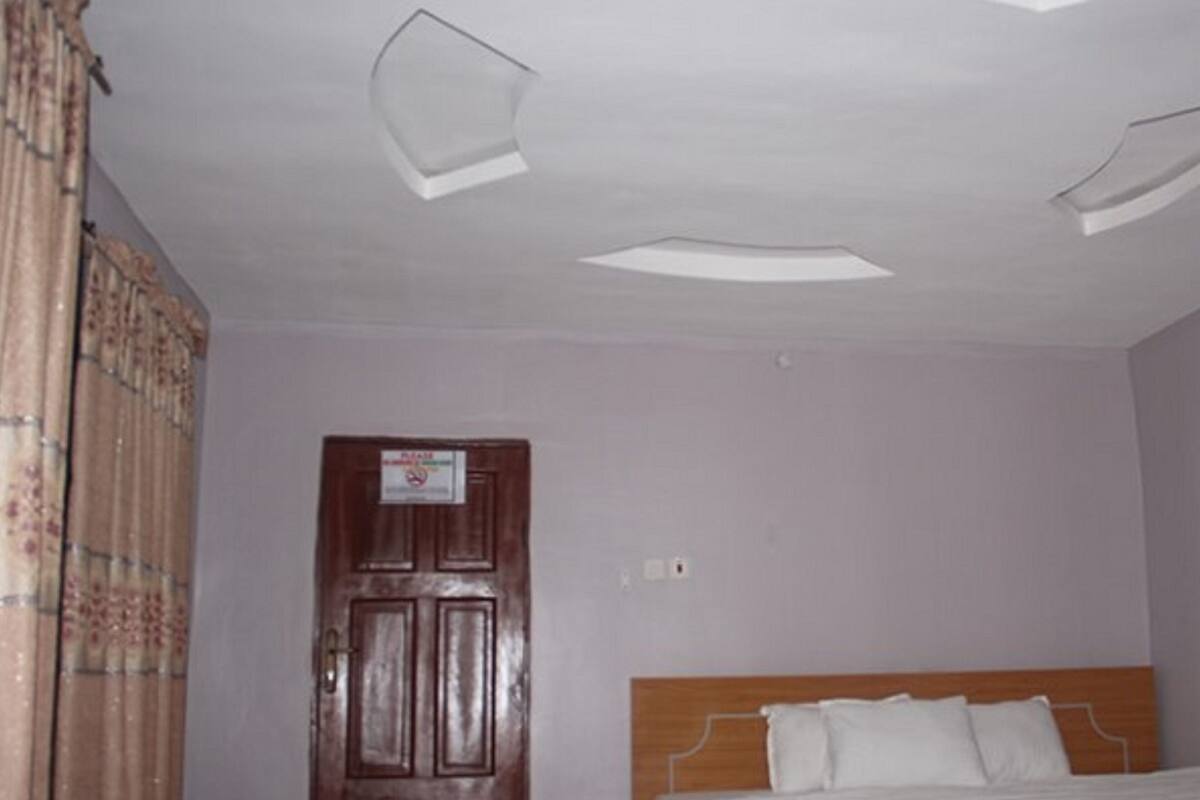 Une chambre à coucher avec un lit en bois, une porte avec une pancarte et un luminaire au plafond.