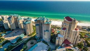 Een hoog hotel met meerdere verdiepingen, een centrale binnenplaats en uitzicht op het strand.