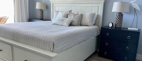 A bedroom with a bed, nightstands, a dresser, and a wall-mounted artwork.
