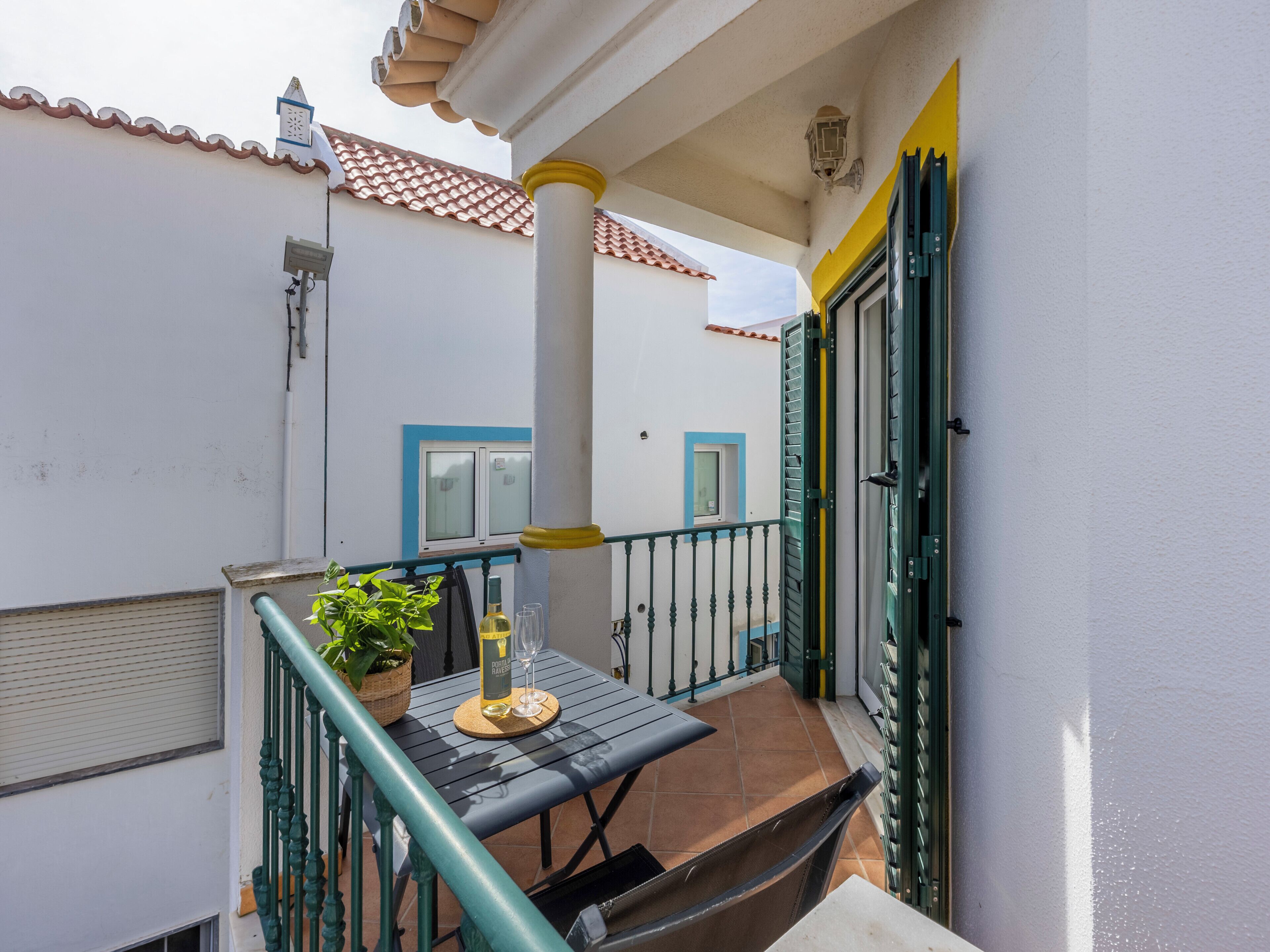 Un balcone con un tavolo, una pianta in vaso e una bottiglia di vino.