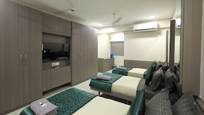 Habitación de hotel con dos camas, televisor, armario y aire acondicionado.