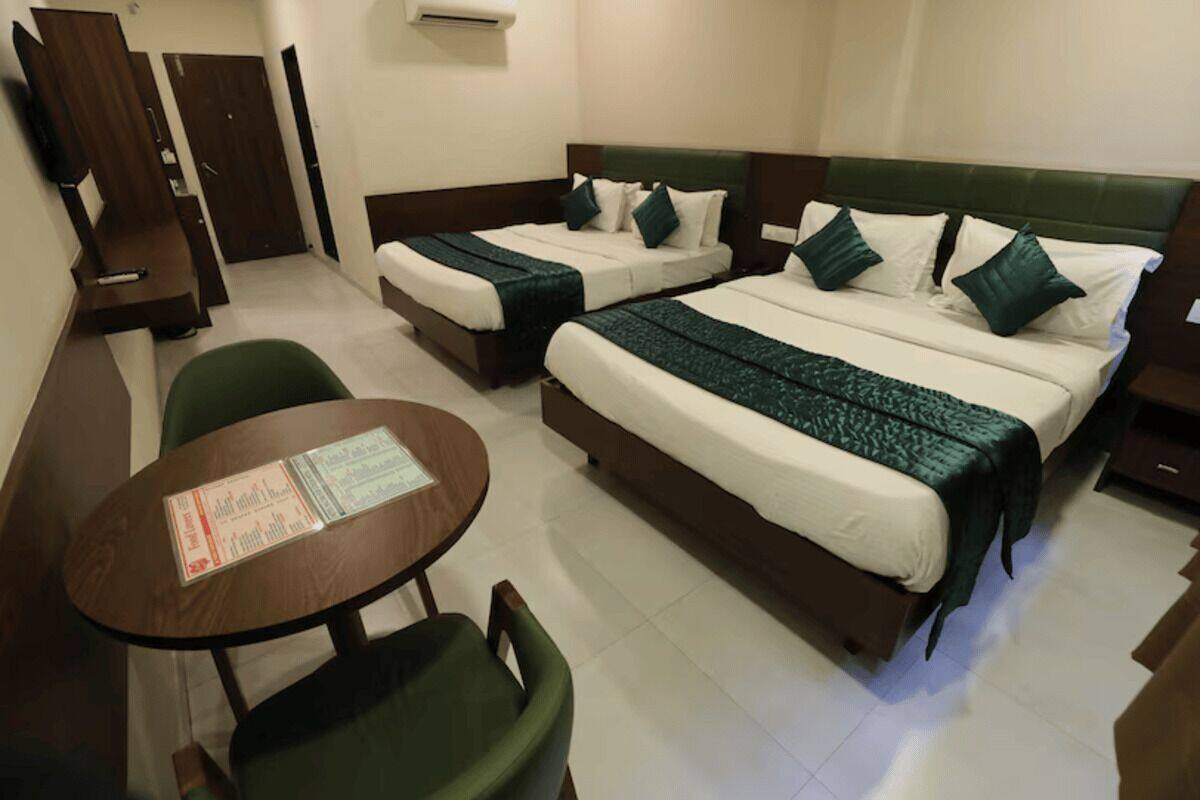 A hotel room with two beds, a desk, and a chair.