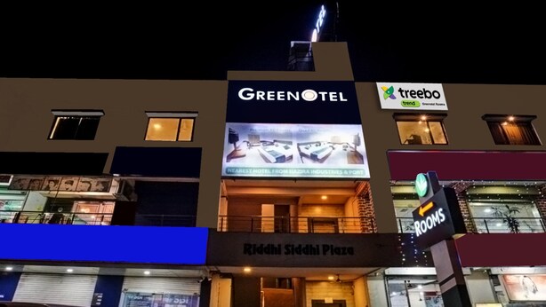 Un hotel llamado Greenotel con un letrero que anuncia habitaciones con aire acondicionado Premium y habitaciones cuádruples con aire acondicionado.
