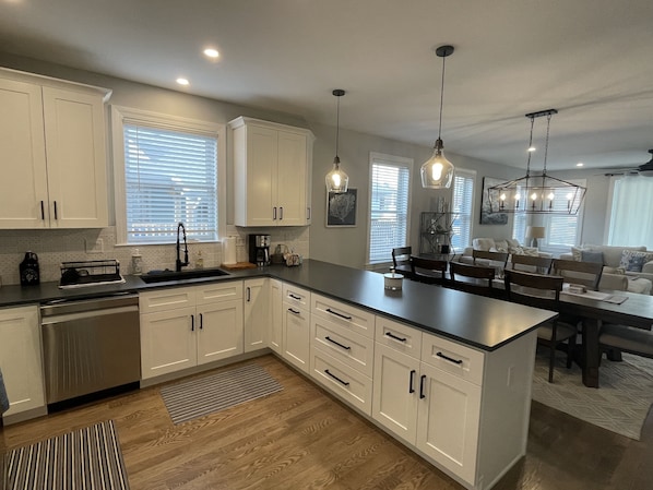 A modern kitchen with white cabinets, a central island, and pendant lighting.
