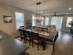 A dining area with a dark wooden table and chairs, a chandelier, and a patterned rug.