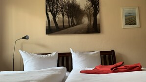 Ett hotellrum med två sängar, en lampa och en tavla på väggen.