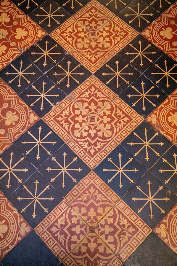 A patterned floor with a diamond design, featuring a mix of red, black, and gold colors. - Beautiful Restored 19th Century Gothic Church (Portlaw)