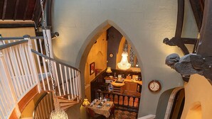 A cozy interior with a staircase, a chandelier, and a dining area.
