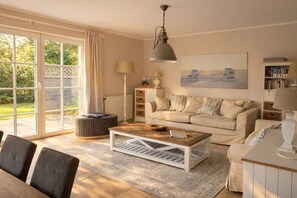 Ein geräumiges Wohnzimmer mit großem Fenster, einer Couch, einem Couchtisch und einem Bücherregal.