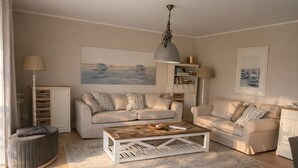 Una sala de estar con dos sofás, una mesa de centro, un aparador y un cuadro en la pared.
