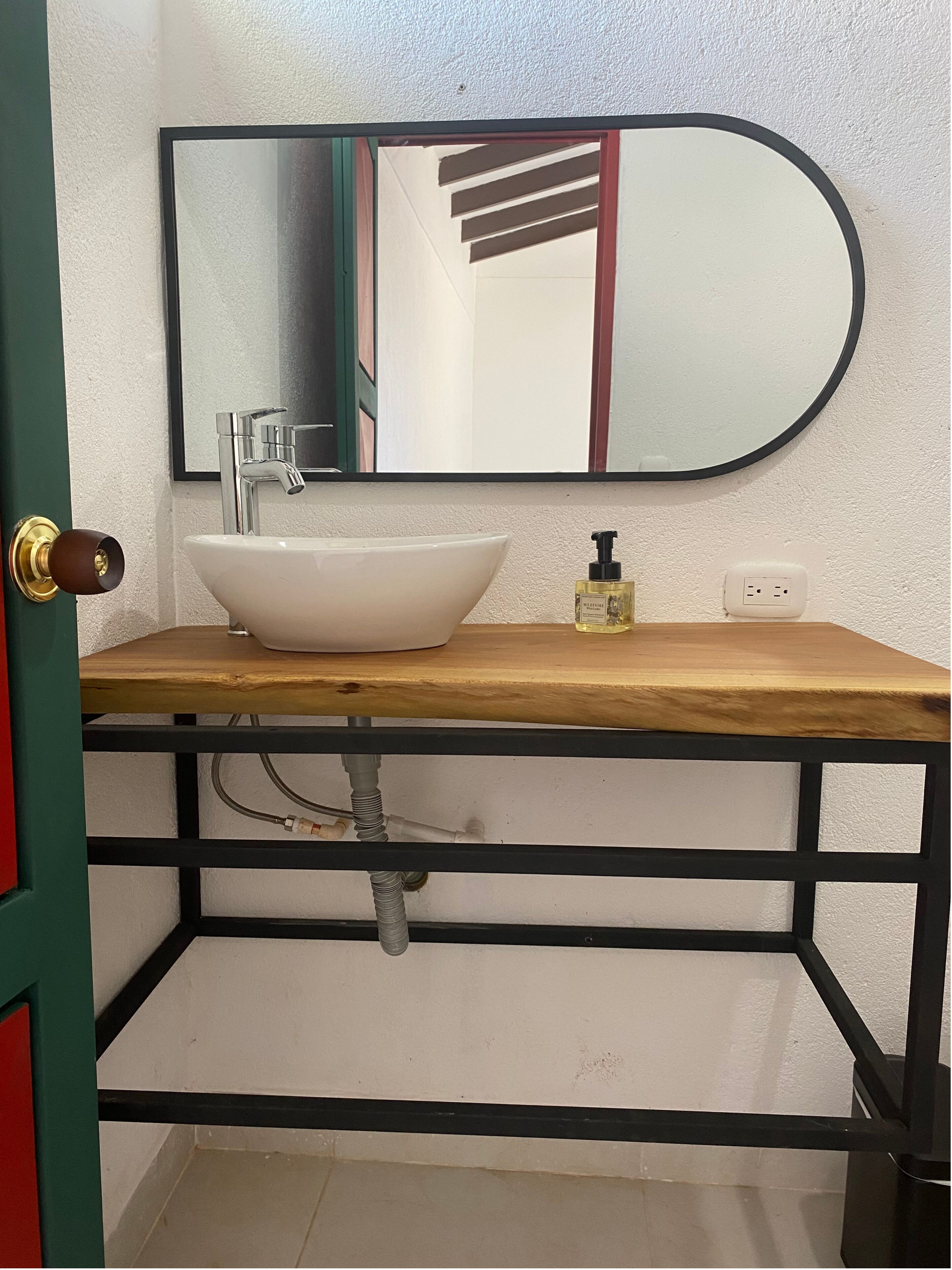 Ein Badezimmer mit einem weißen Waschbecken, einem Spiegel und einer Holzausstattung.