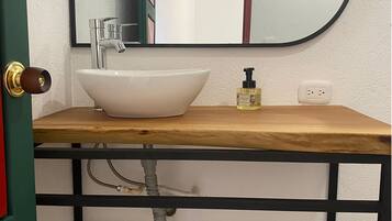 Ein Badezimmer mit einem weißen Waschbecken, einem Spiegel und einer Holzausstattung.