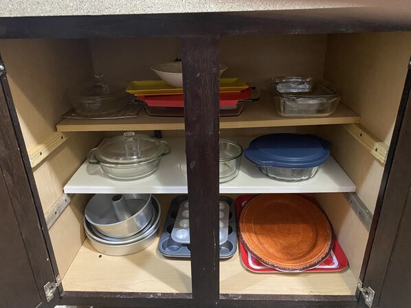 Un mueble de cocina con varios estantes que contienen distintos utensilios de cocina.