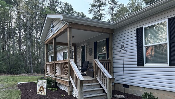 A house with a covered porch, a staircase leading to the entrance, and a small garden area.