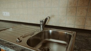 Un lavamanos de acero inoxidable con un grifo moderno, dispensador de jabón integrado y desagüe.
