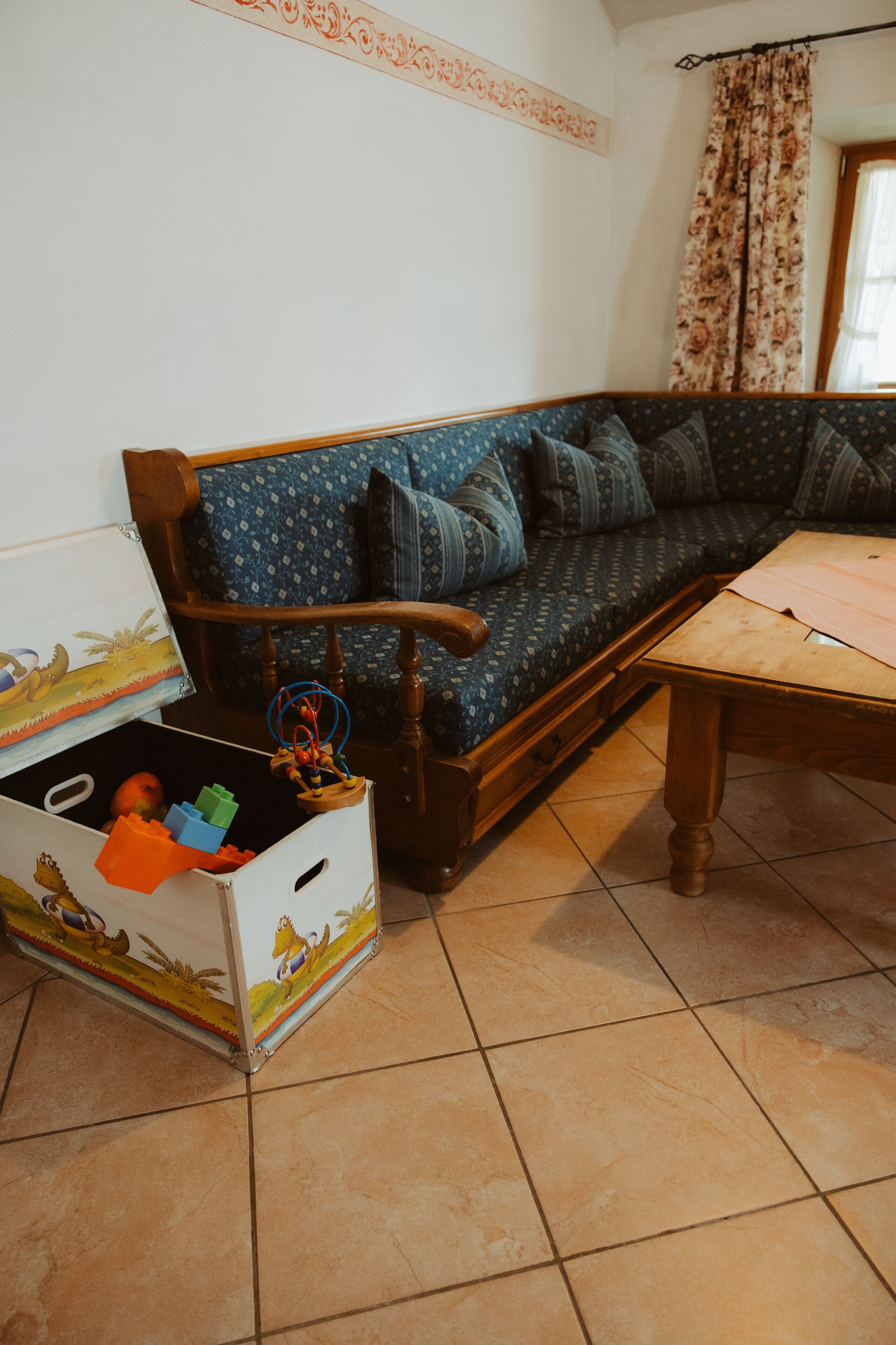 Un salon avec un canapé, une table basse en bois et une boîte de rangement contenant des jouets.