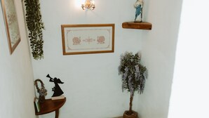 Una escalera con barandilla de madera, una mesita con adornos, una lámpara de pared y un cuadro enmarcado.