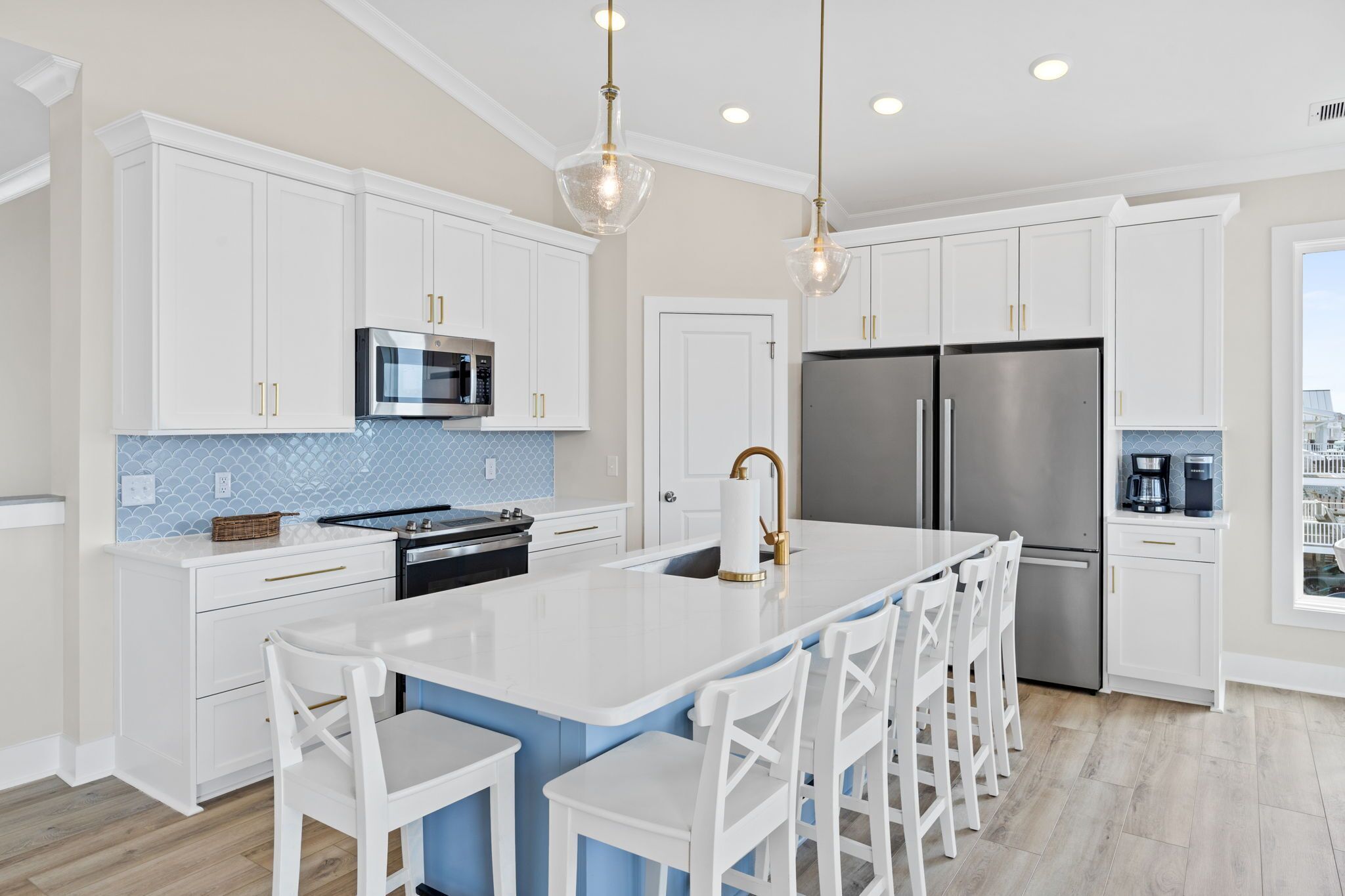 A modern kitchen with white cabinetry, stainless steel appliances, and a central island with bar seating.