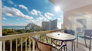 A balcony with a round table and chairs, overlooking a beach and buildings. - Tops'l Summit 812 ~ Gulf views and quick walk to the beach (Miramar Beach)