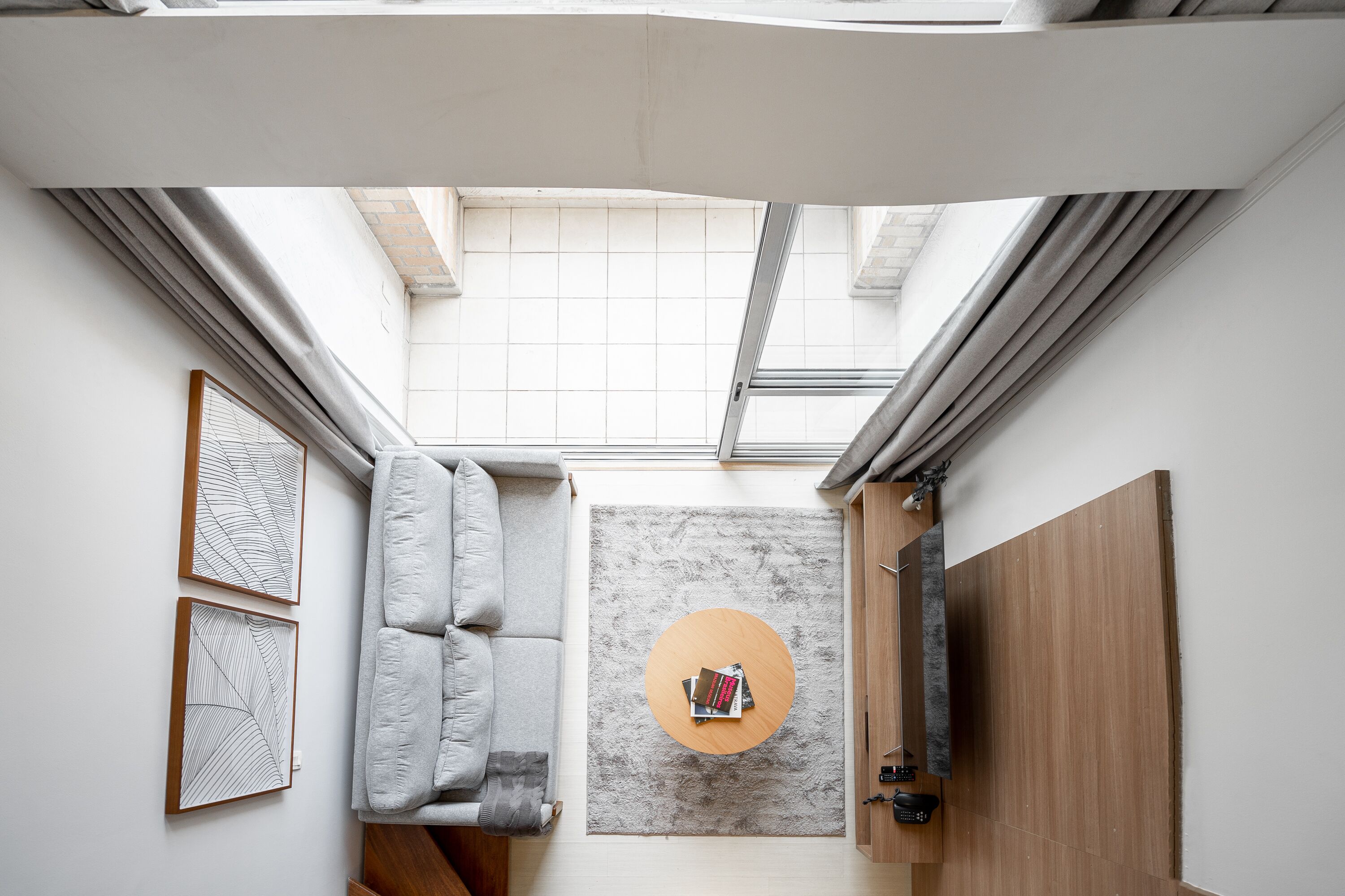 A compact living space with a grey sofa, a round coffee table with books, and a grey rug.