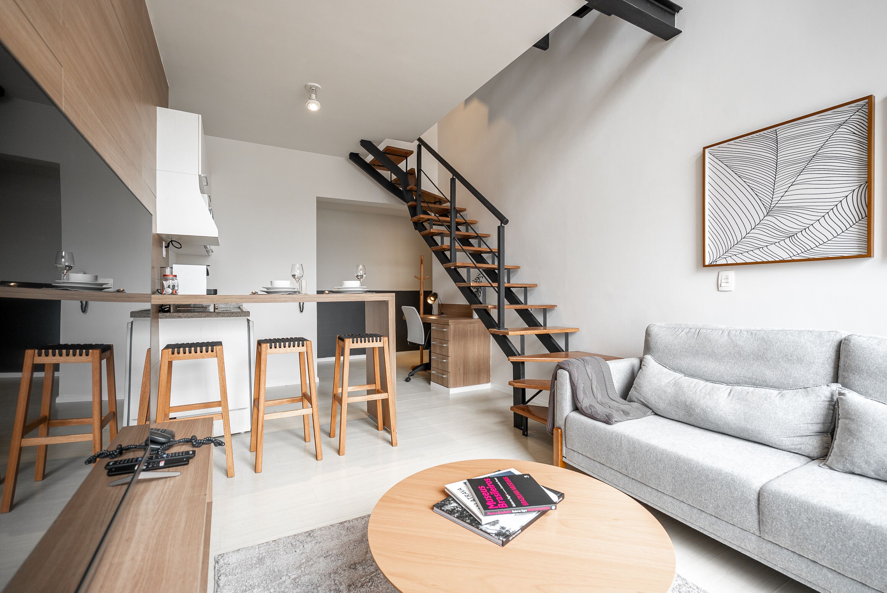 A modern living space with a kitchen, dining area, and a staircase.