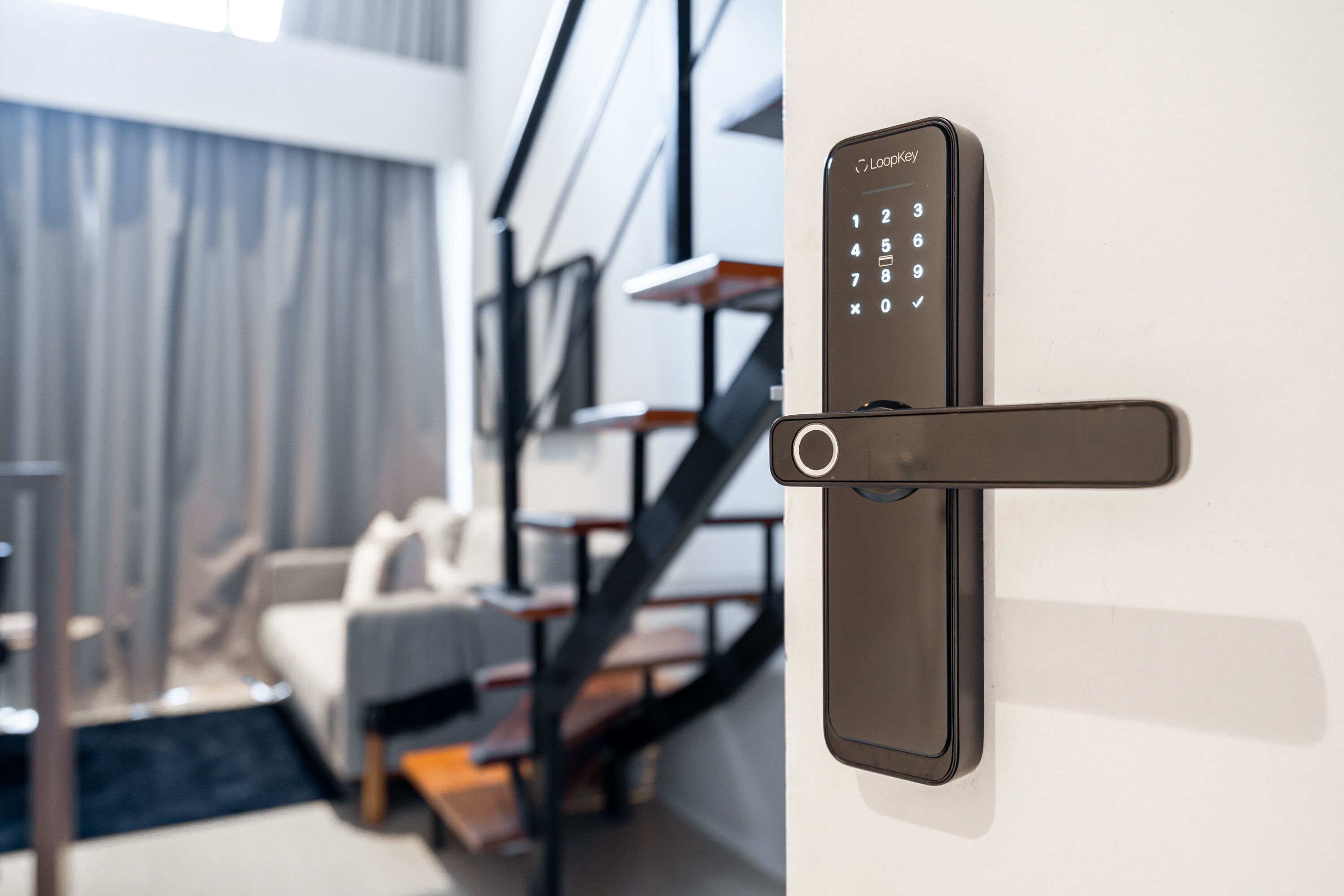 A modern room with a built-in electronic door lock, a staircase, and a sofa.