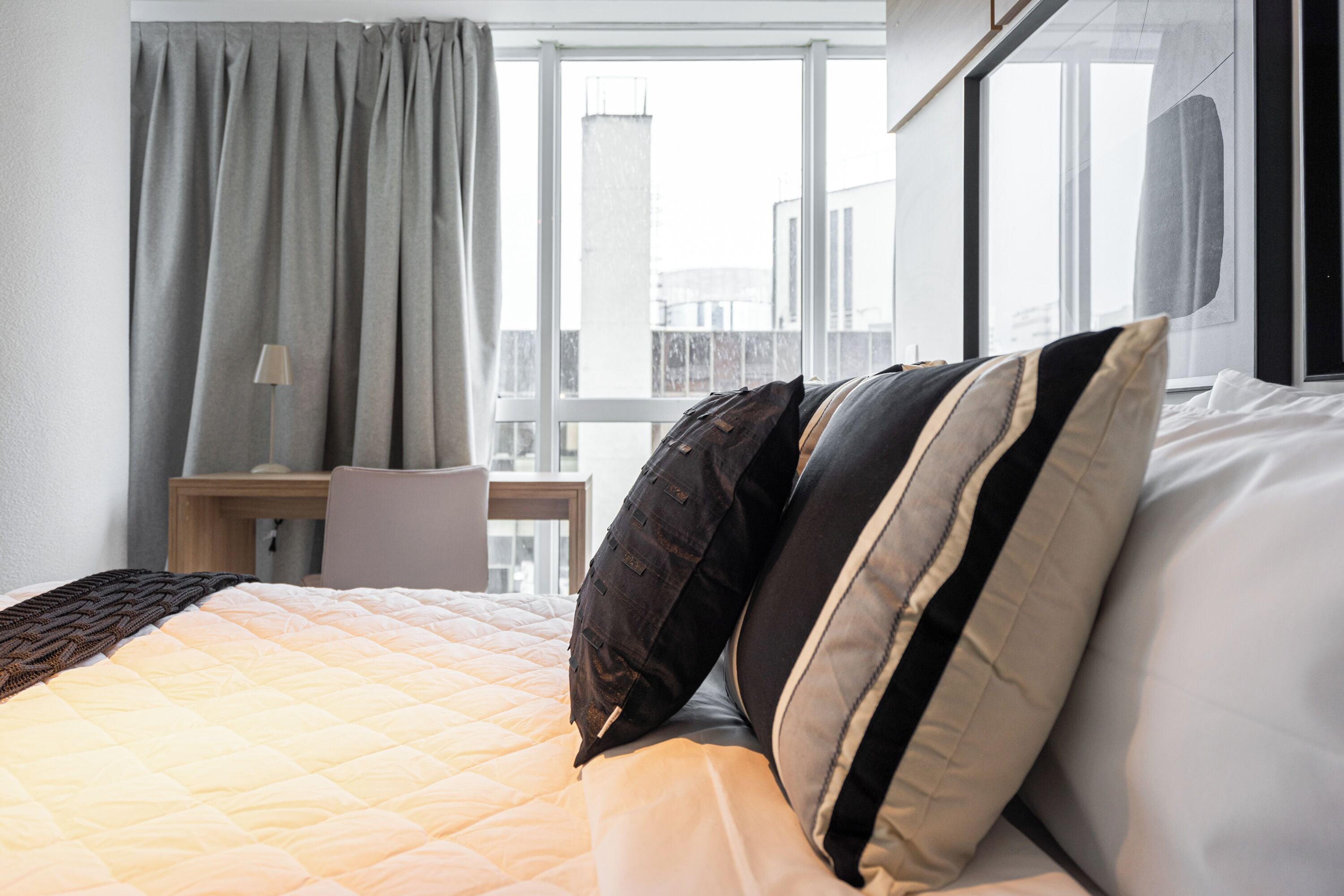 Een hotelkamer met een bed, een bureau en een raam met gordijnen.