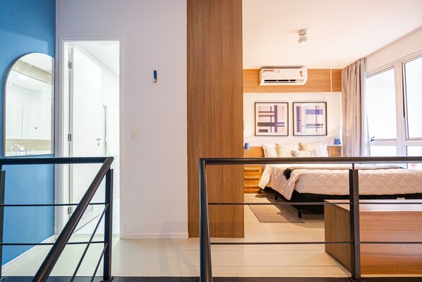 A modern bedroom with a bed, bedside tables, a wardrobe, and a large window.