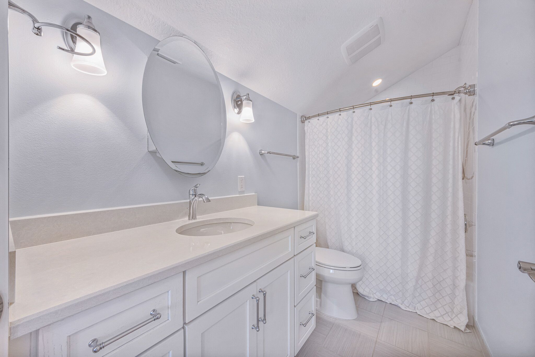 Un baño moderno con tocador doble lavamanos, inodoro y cortina de ducha.