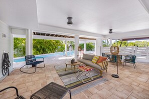 An outdoor patio with a pool, seating area, and large windows. - The Hammock House: Bright and modern pool home with outdoor living space (Anna Maria)