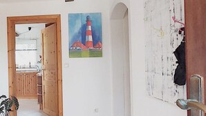 Una habitación con puerta de madera, un cuadro de un faro y una pizarra con notas.
