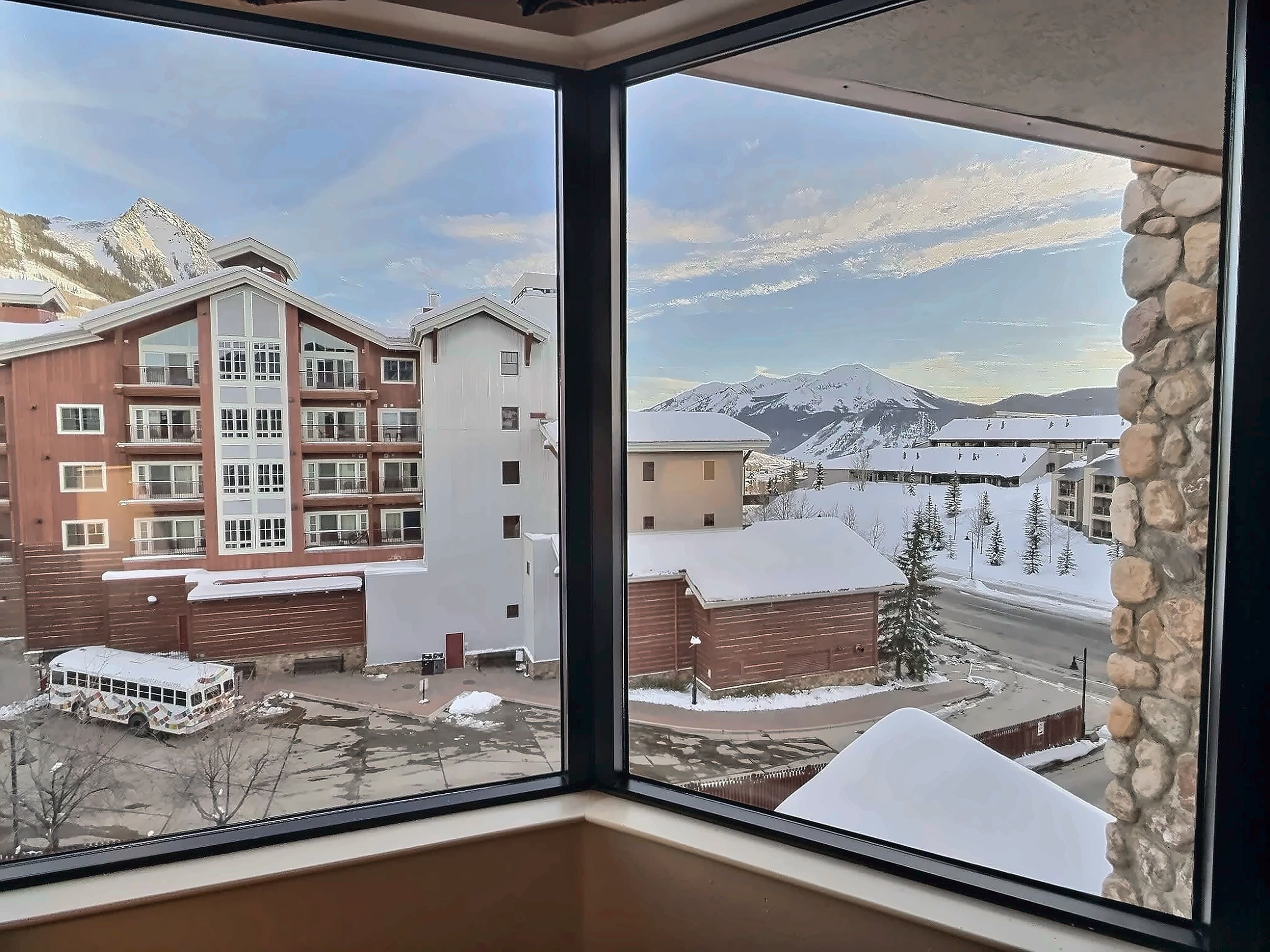 A multi-story building with a snow-covered roof and a mountain view.