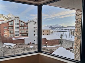 A multi-story building with a snow-covered roof and a mountain view.