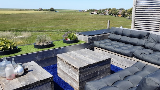 An outdoor seating area with a sofa, coffee table, and planters. - 6p Luxury apartment with panoramic roof terrace (Burgerbrug)
