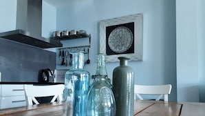 A kitchen with a wooden table, three glass bottles, and a metal container. - 6p Luxury apartment with panoramic roof terrace (Burgerbrug)