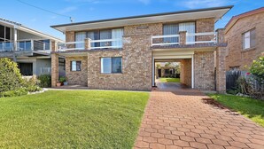 A two-story house with a brick facade, a balcony, and a well-maintained lawn. - 1/15 Dalmeny Drive, Kianga (Kianga)