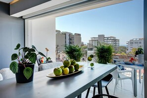 A balcony with a dining table, potted plants, and a view of buildings.