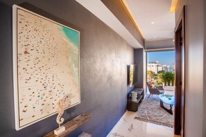 A modern interior with a large abstract painting, a wooden sculpture, and a view of the city through a large window. - Chic 1BR in Romantic Zone w/pool (Puerto Vallarta)