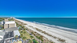 A beachside hotel with a view of the ocean, a parking area, and a building with a flat roof. - 🌊Newly Renovated Oceanfront | Awesome Amenities | Caribbean Resort 803🌊 (Myrtle Beach)