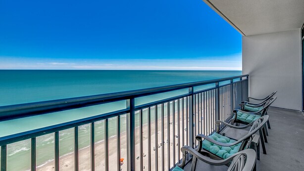 Ein Balkon mit Blick auf den Ozean, ausgestattet mit mehreren Liegestühlen.