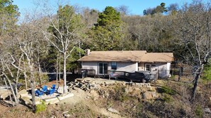 A single-story house with a front porch, a small deck, and a flag. - Secluded Lakehouse Right on Lake Eufaula! (Crowder)