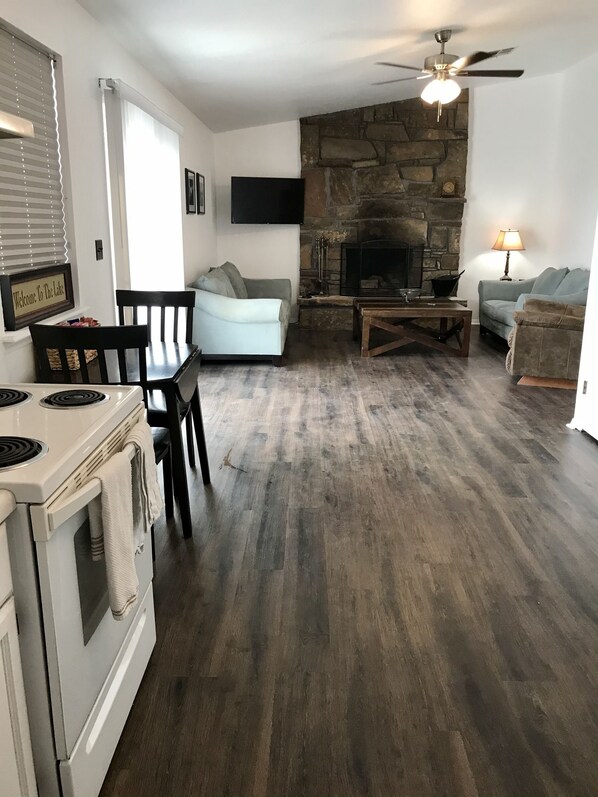 Cocina moderna con estufa, mesa de comedor y sillas. Hay una chimenea de piedra con un televisor montado encima.