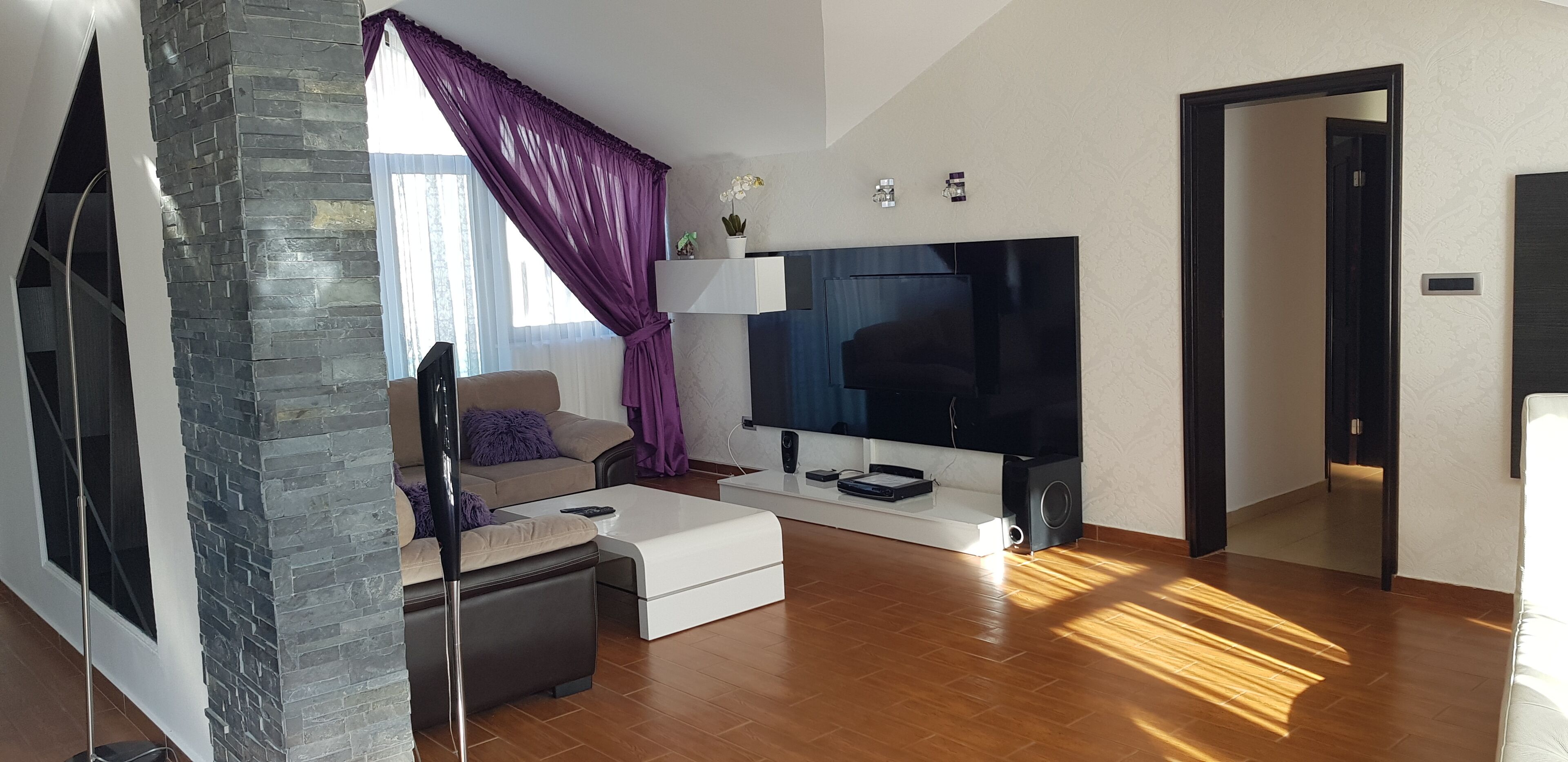 A modern living room with a stone accent wall, a sofa, a coffee table, and a flat-screen TV.