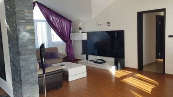 A modern living room with a stone accent wall, a sofa, a coffee table, and a flat-screen TV.