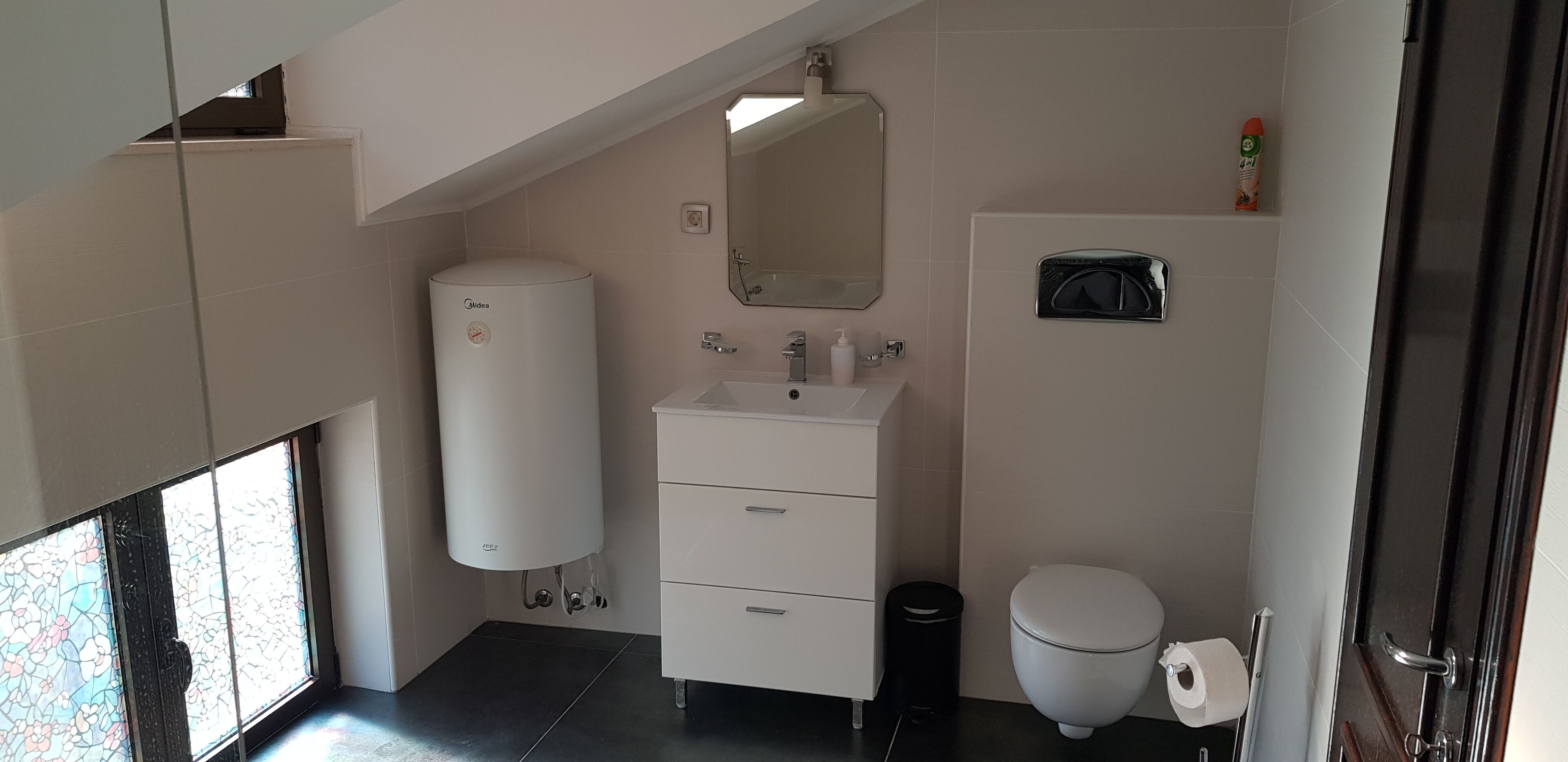 Une salle de bain moderne avec un lavabo, un miroir et des toilettes, le tout de couleur blanche.