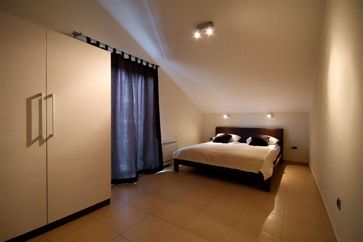 Une chambre à coucher avec un lit, une armoire, un radiateur et un luminaire au plafond.